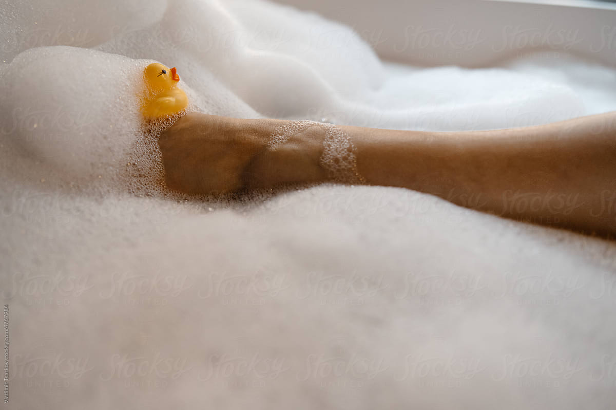 Crop woman leg with rubber duck in bathtub