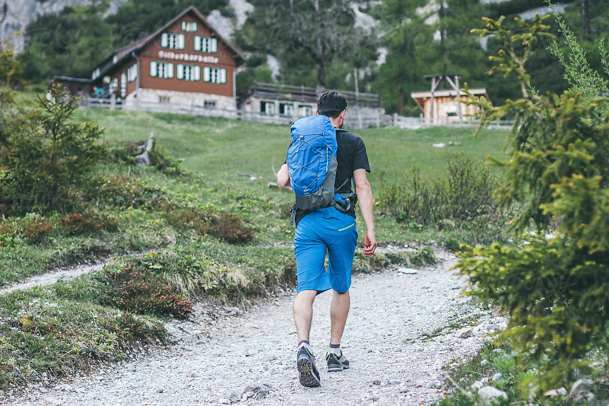 young male hiker walking on a trail to a managed alpine cabin