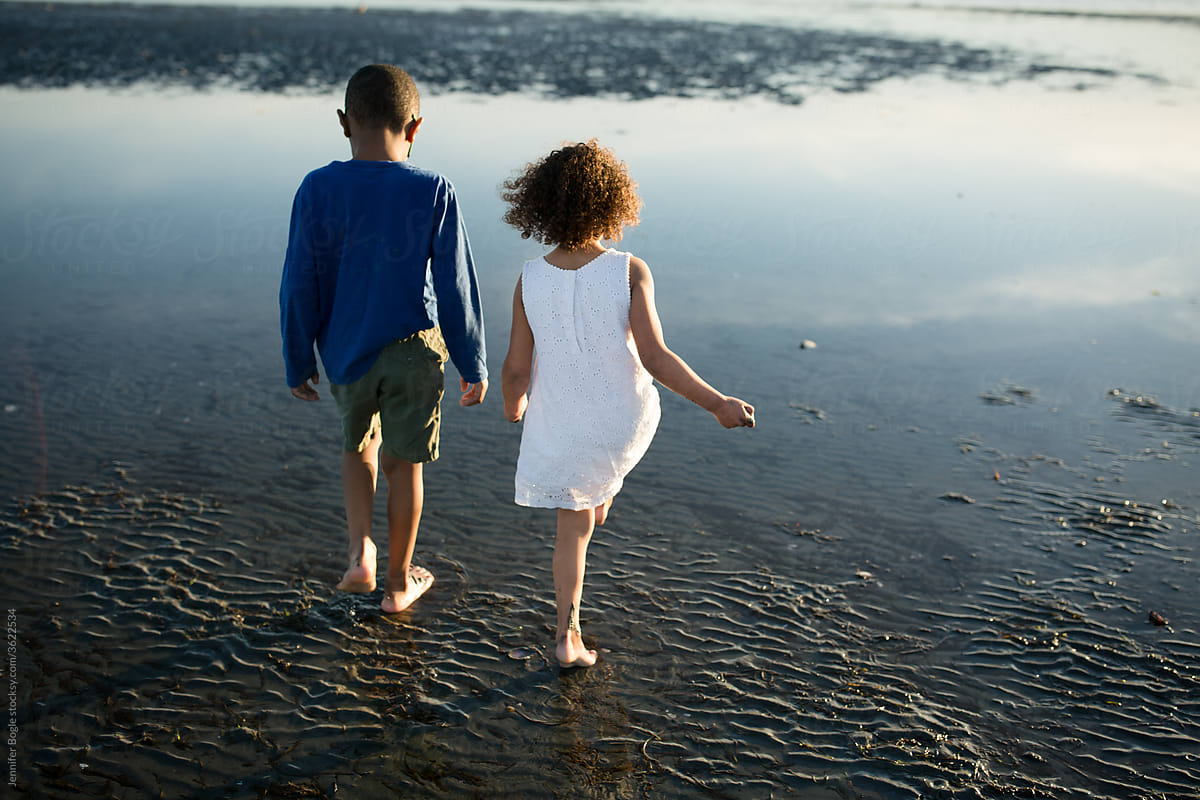Brother and sister walk across tide pools
