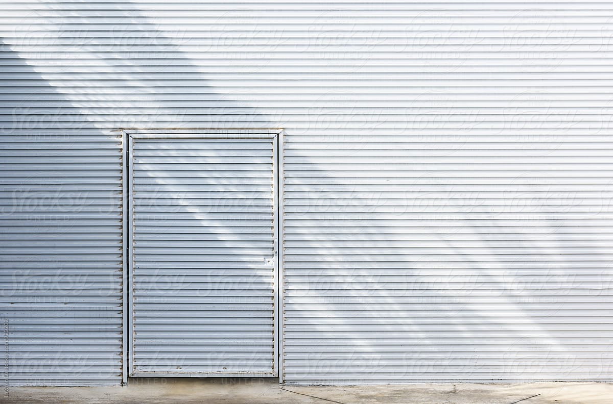 White metal siding wall with shadow and door