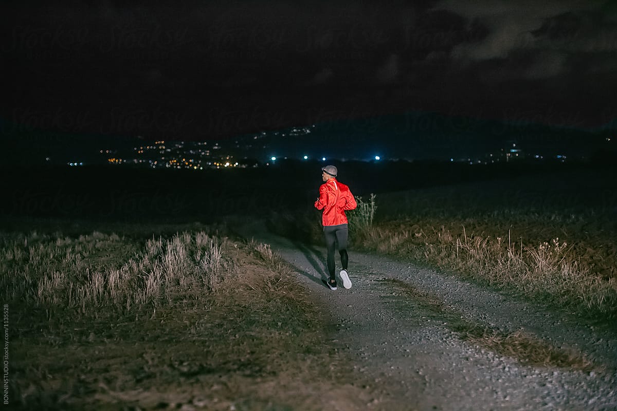 Man running on a field path at night.