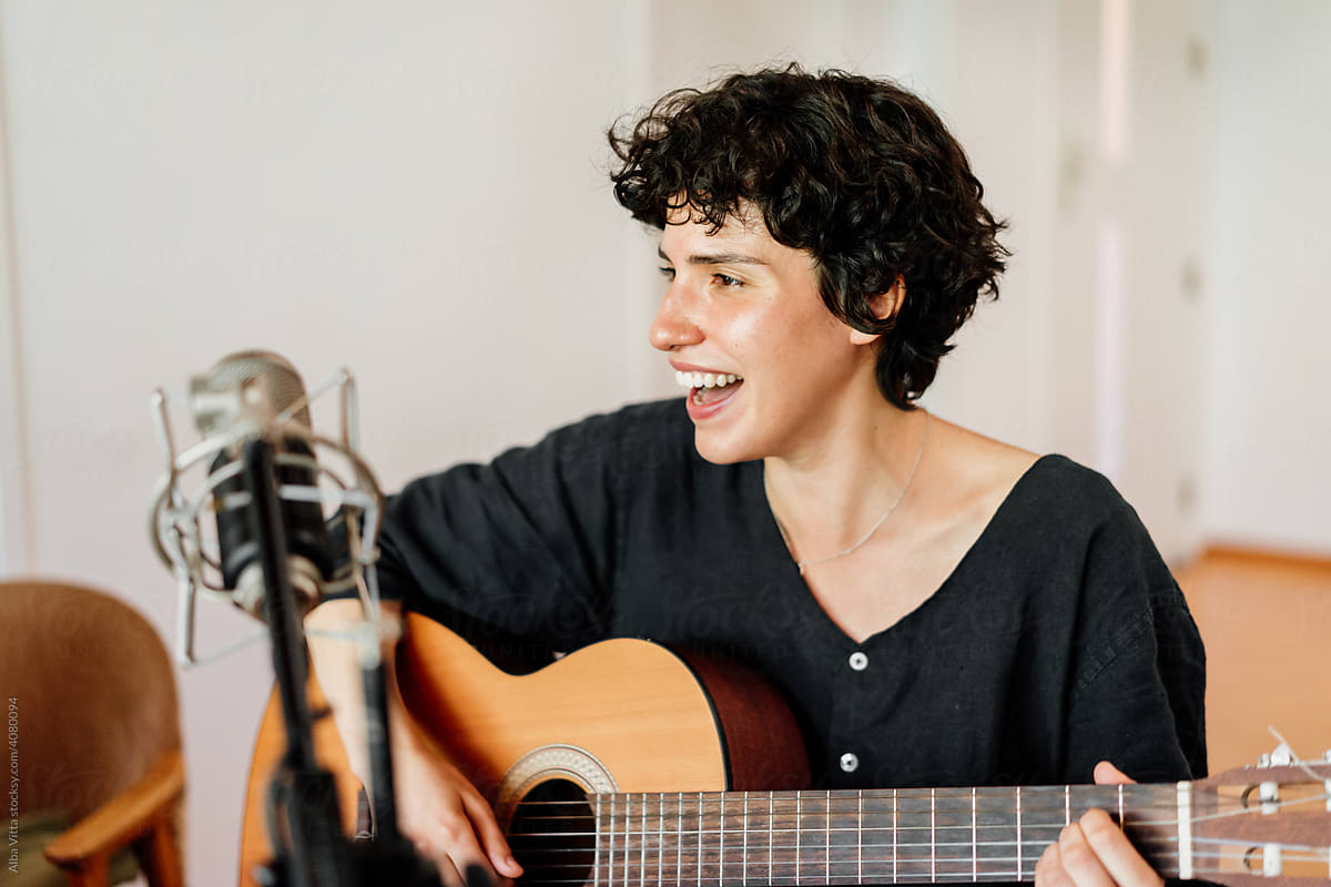 Smiley young woman playing music at home studio