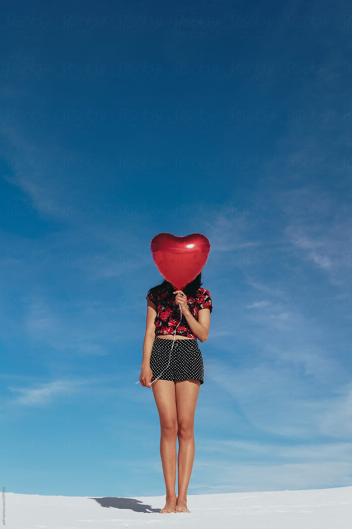 Young woman hiding her face with a heart balloon