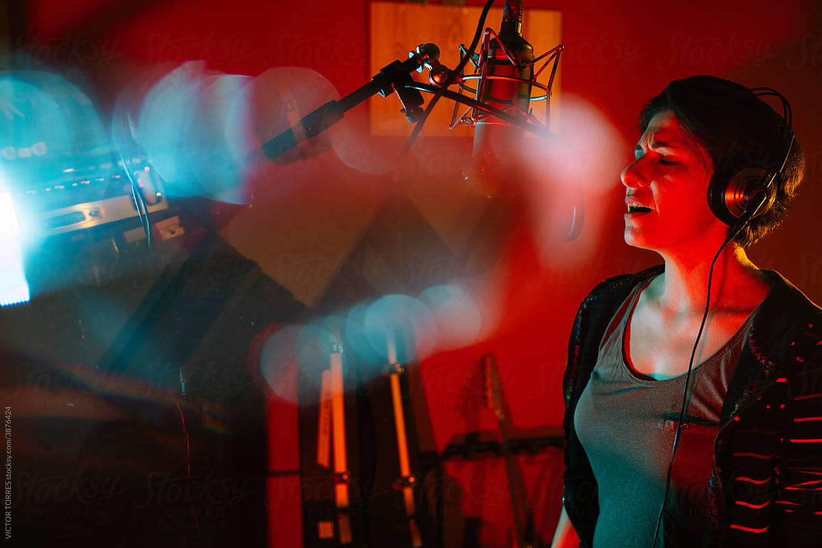 Vocalist singing into professional microphone in recording studio