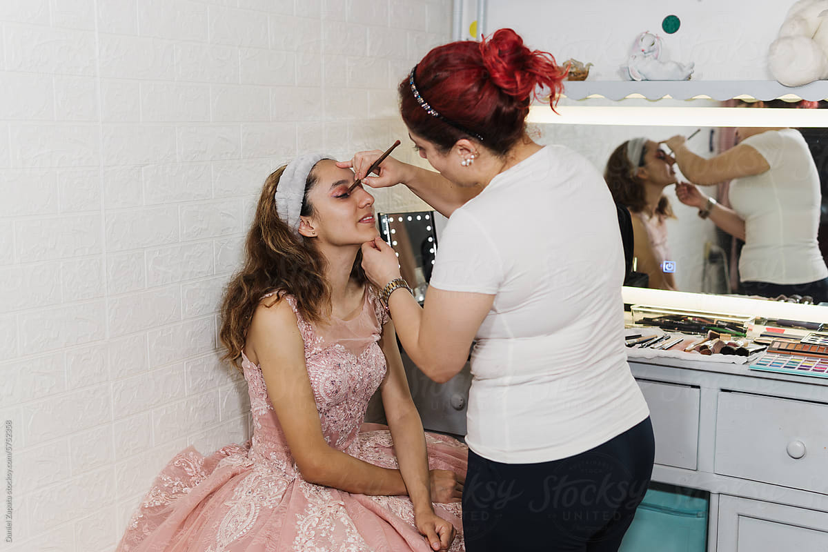Makeup artist applying makeup to a quinceañera.