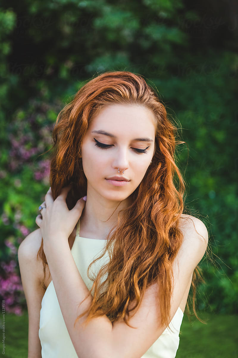 Beautiful Young Redhead Arranging her Long Hair in a Natural Env