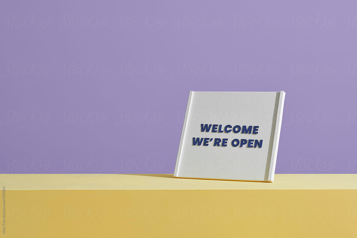 Welcome we\'re open sign on table over purple