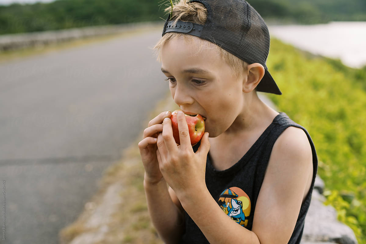 little boy biting into an apple during a break on his hike