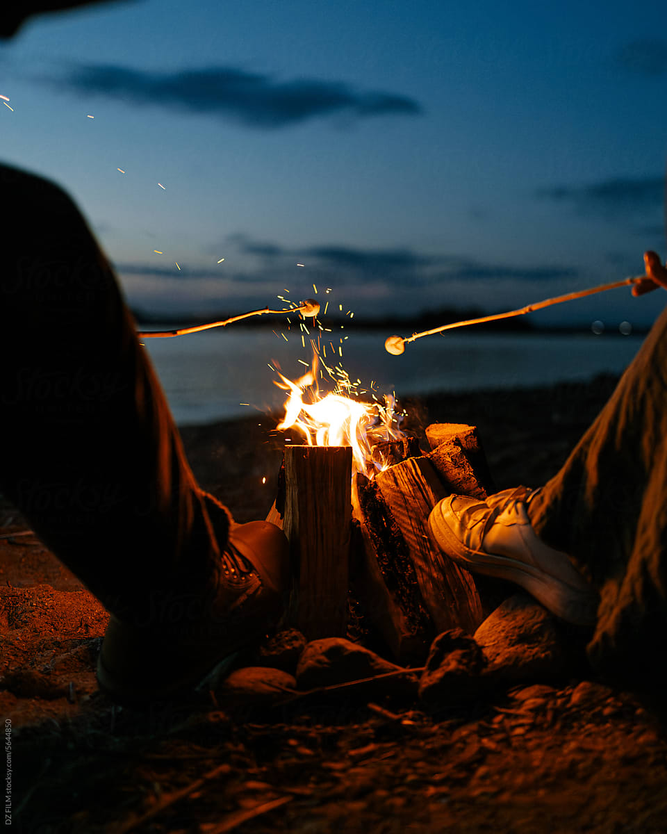 A man and a woman roast marshmallows on a bonfire