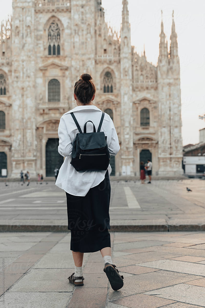 Young woman from behind exploring Milan's Duomo at sunrise