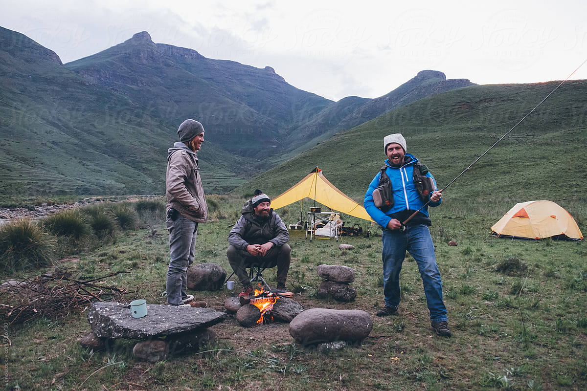 flyfishermen friends fooling around by a camp fire in the mountains