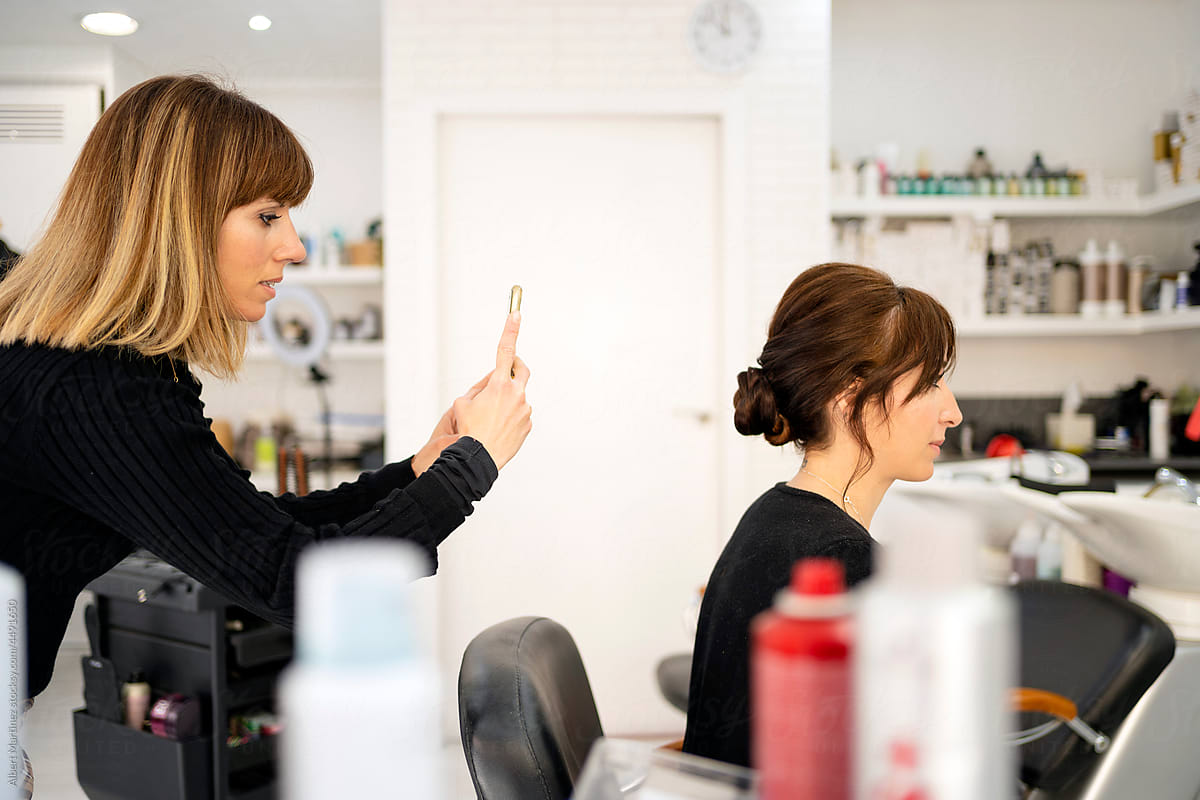 Hairdresser taking picture of female client in salon