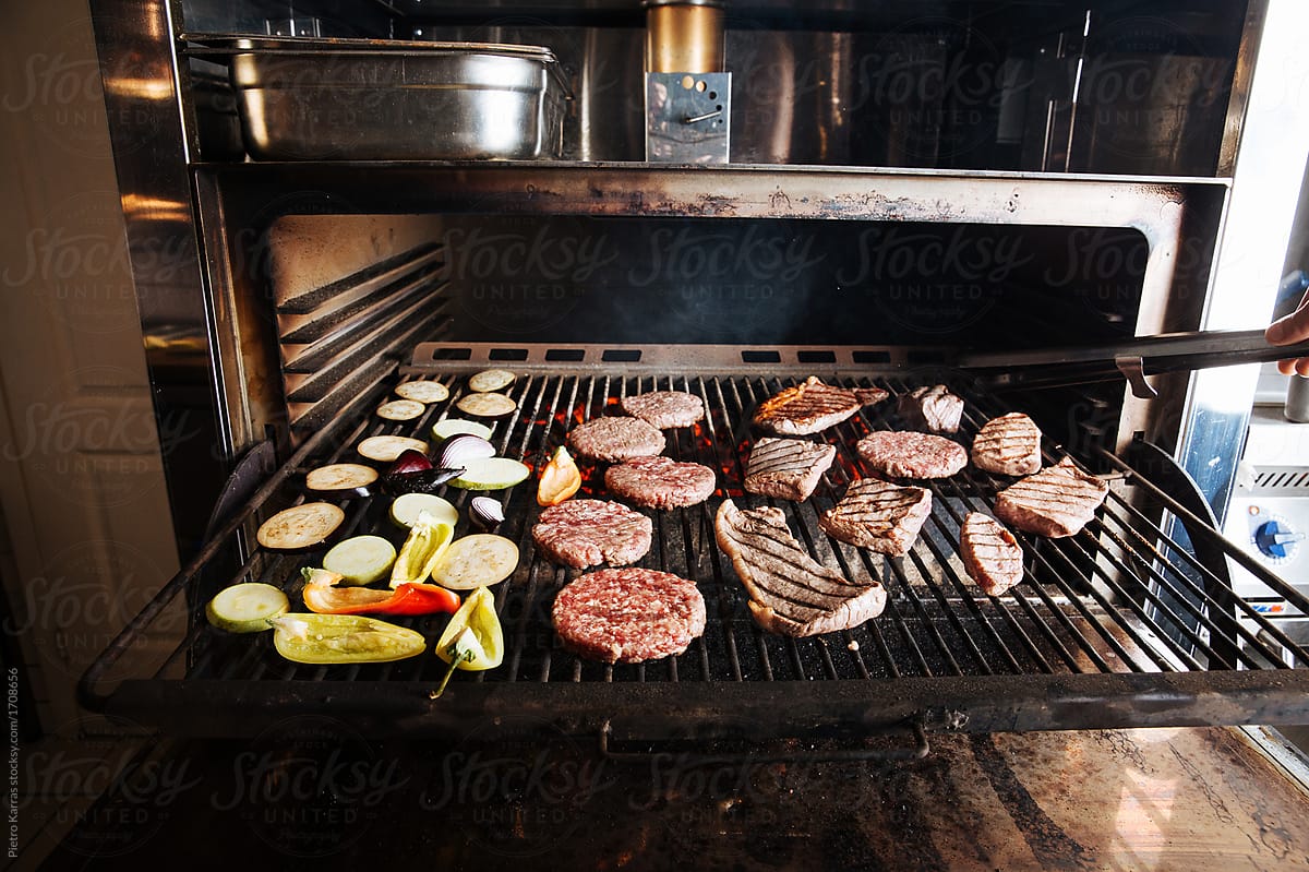 Meat and vegetables cooking on grill, at professional cafe kitchen