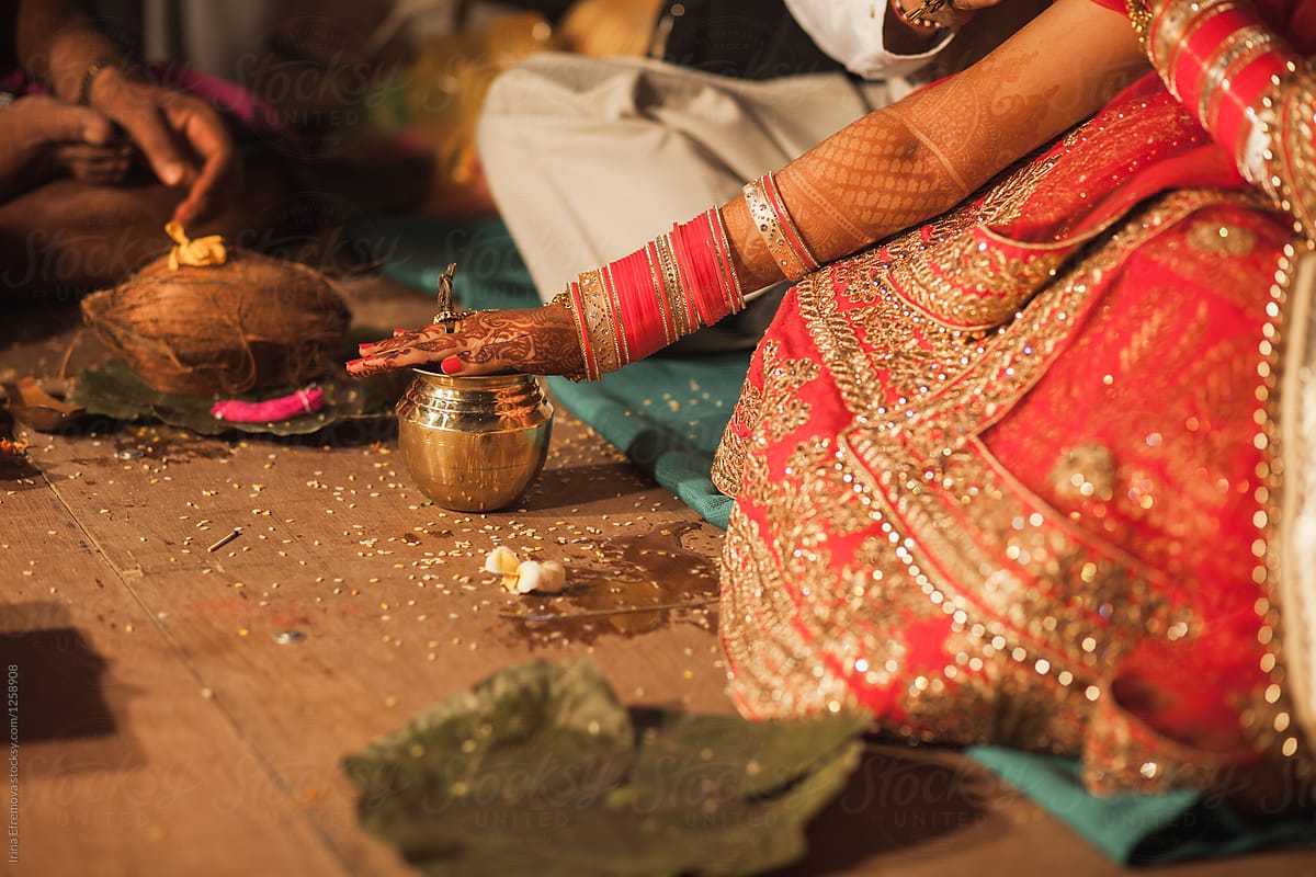 Bride\'s hand on a golden cup during a hindu wedding ceremony