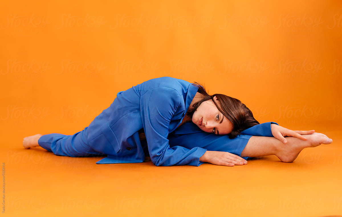 Young woman with stretched legs lying on orange floor
