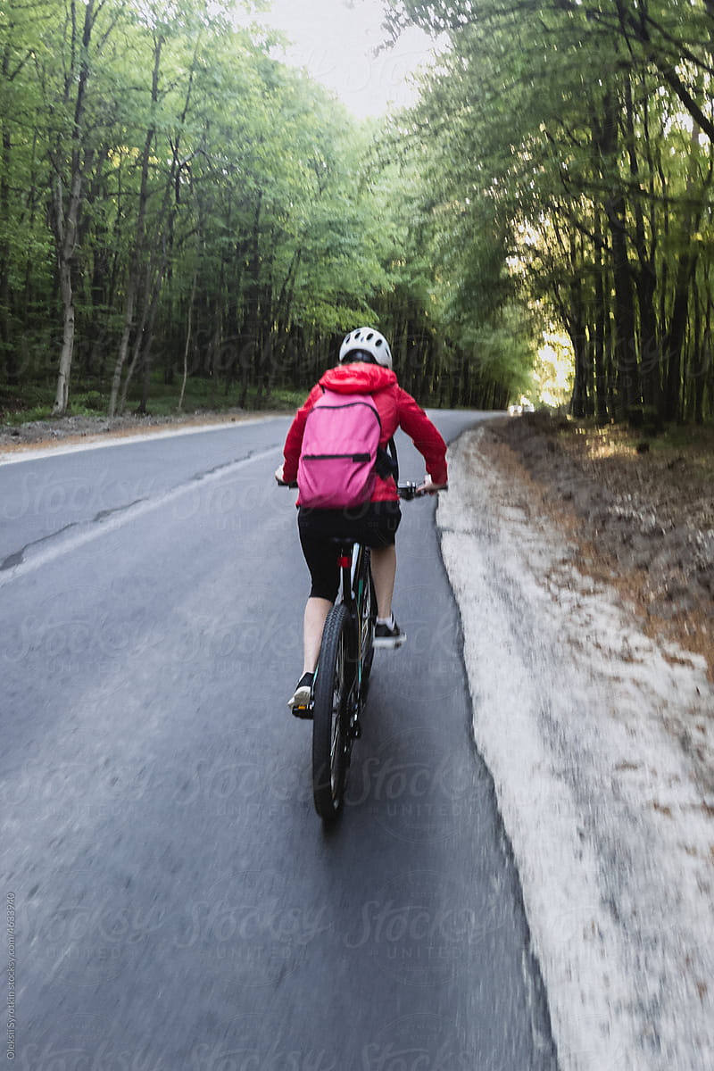 Biker travelling on main road near forest