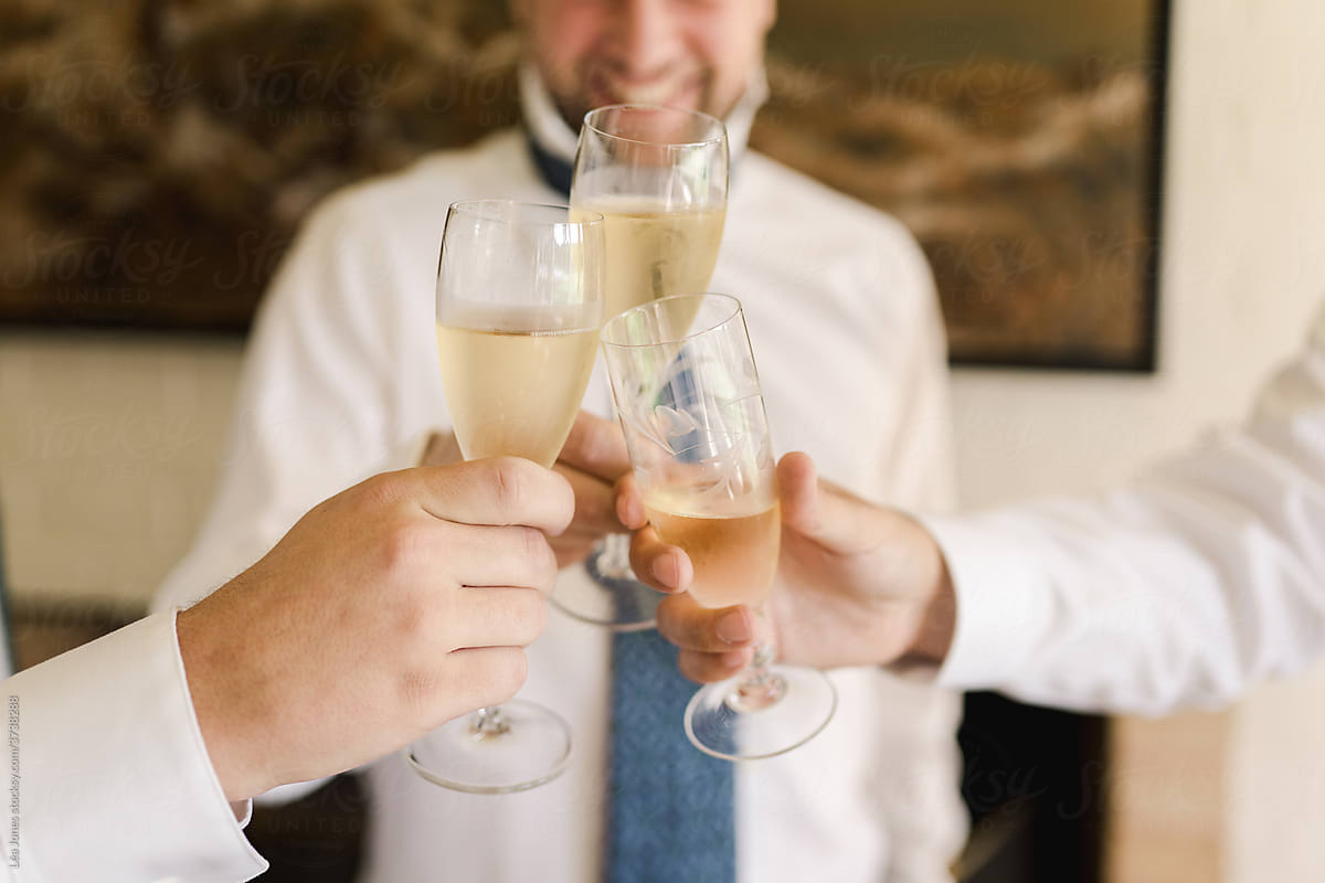 happy groom holding champagne with groomsmen