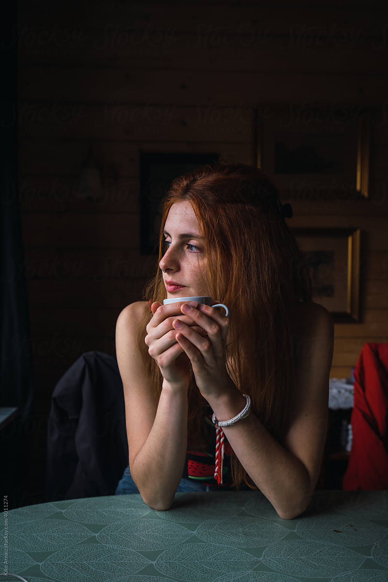 Young woman with hot beverage looking away