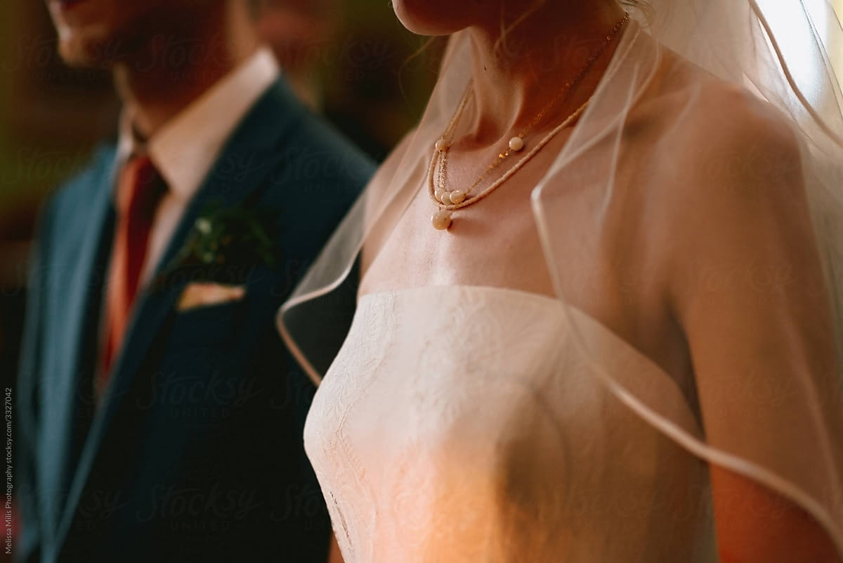 close up of bride and groom standing next to each other with focus on necklace of the bride