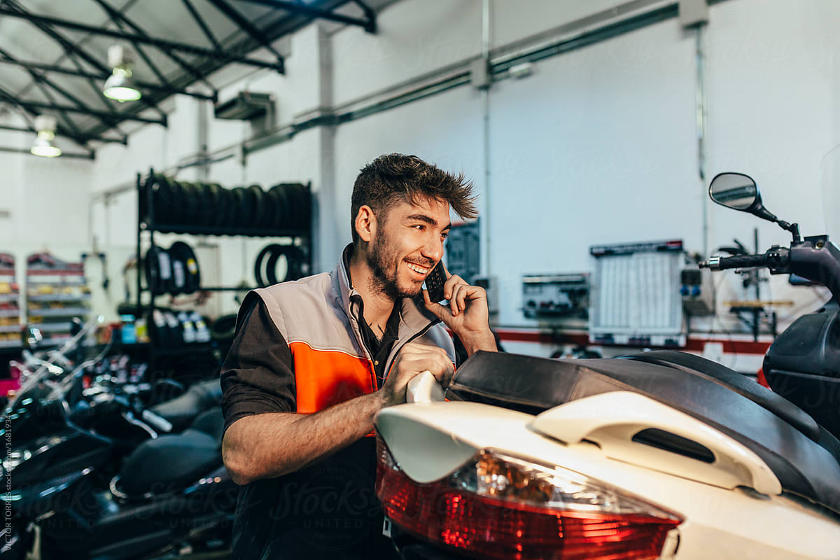 Mechanic using a phone in the motorbike workshop