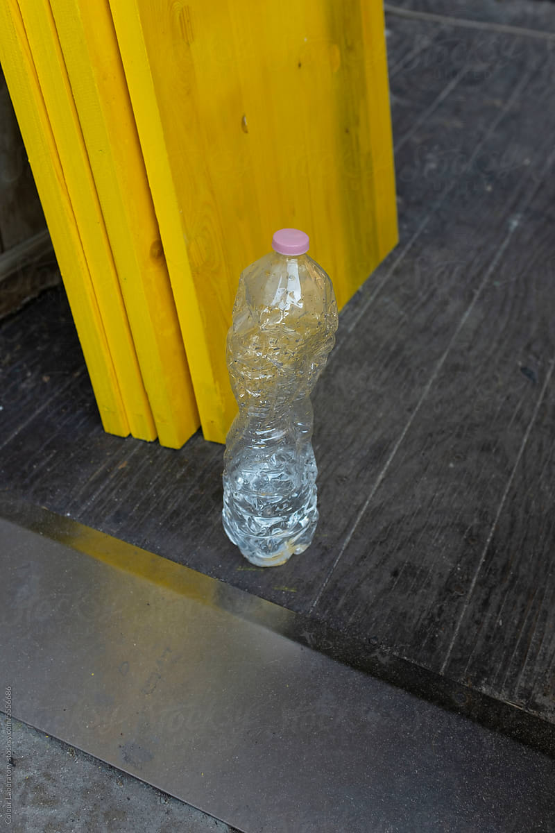 Plastic water bottle with pink etiquette front of bright yellow wall