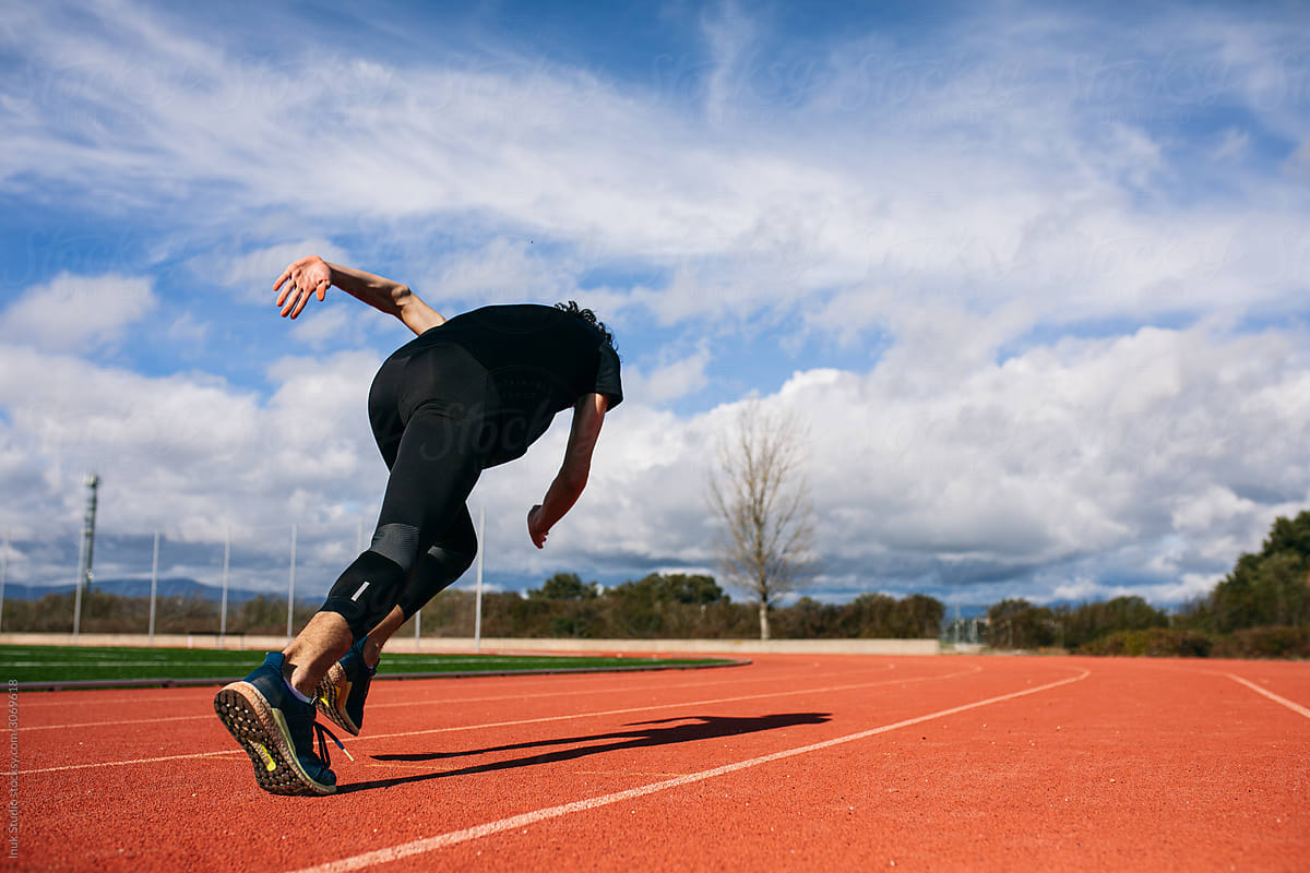 Unrecognizable sportsman running on track