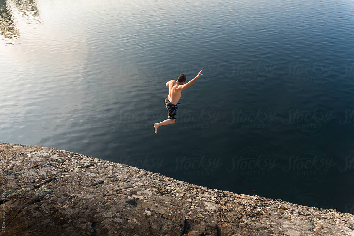 Man Leaping Into Summer Lake From Cliff Near Killarney Canada By Stocksy Contributor Jp Danko