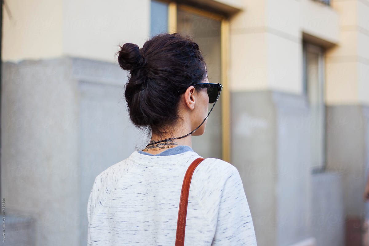 Woman with a tattoo on her neck on the street. From the back.