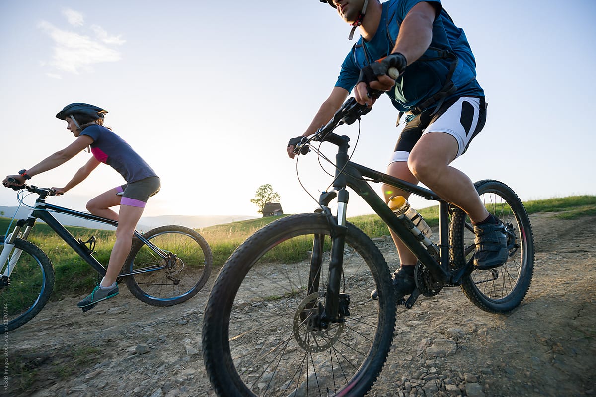 Sportive Couple Riding Mountain Bikes Off Road During Susnset Del Colaborador De Stocksy Ibex