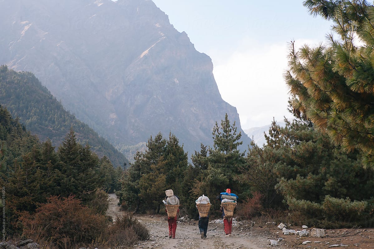 Three porters walking along the trail in the Annapurna Circuit.