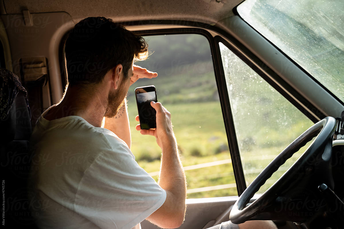 Man taking photo with phone inside camper van