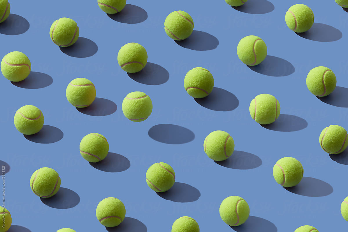 Diagonal pattern of yellow tennis balls on violet studio background