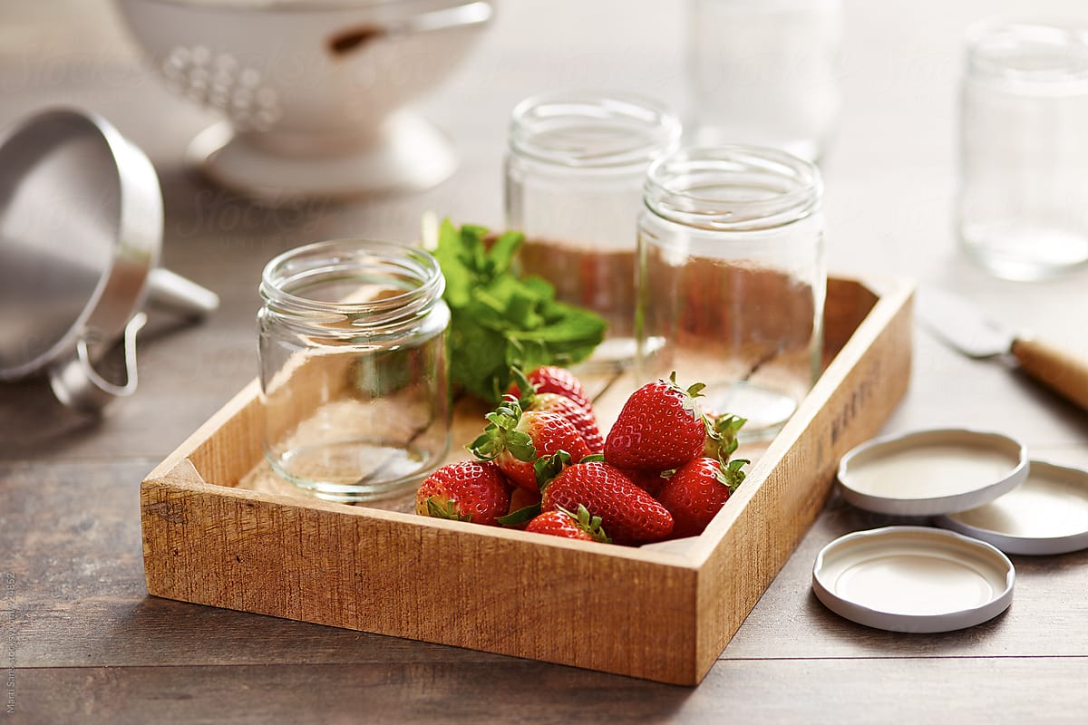 Glass cans and strawberries in wooden tray