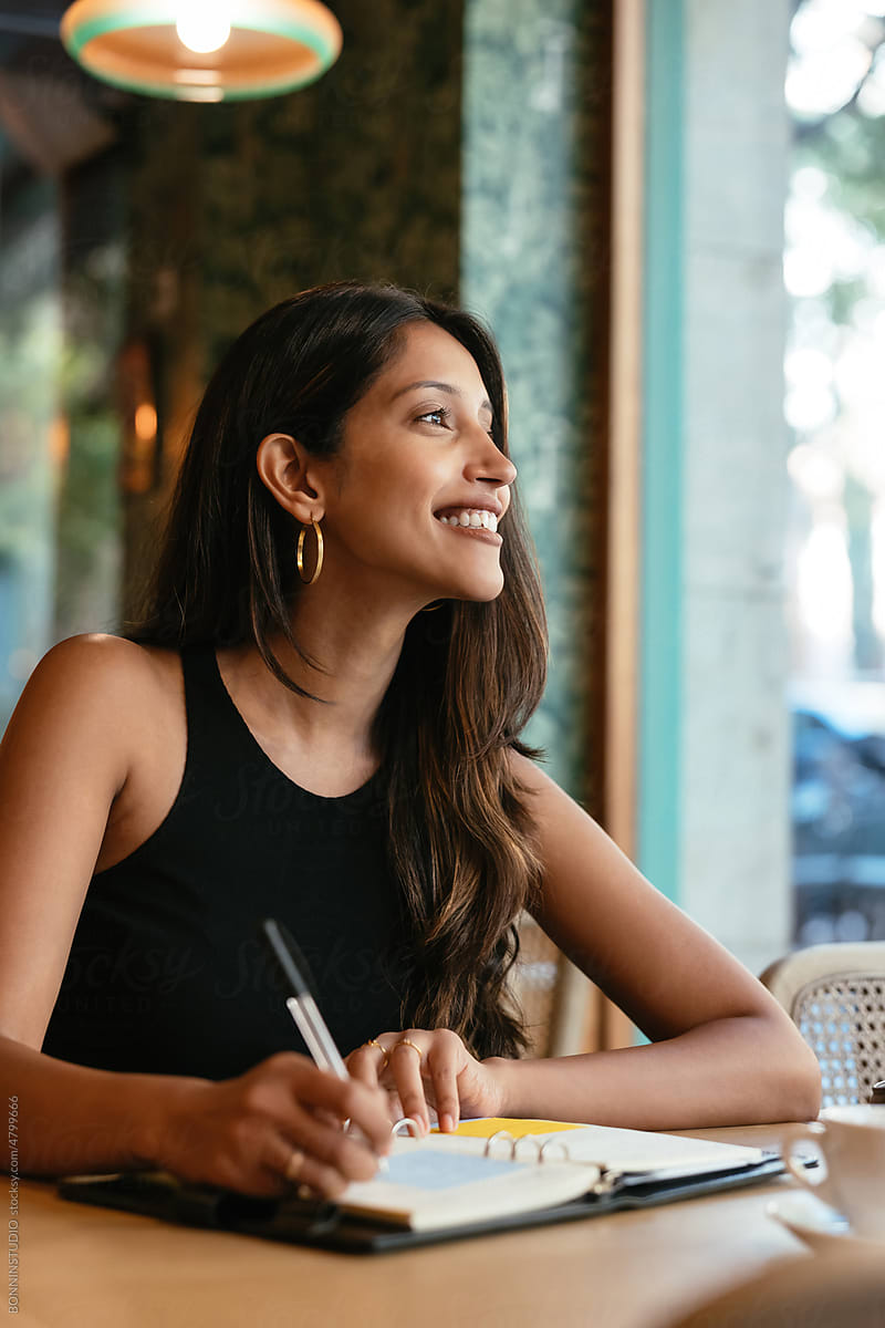 Cheerful South Asian woman making notes in restaurant