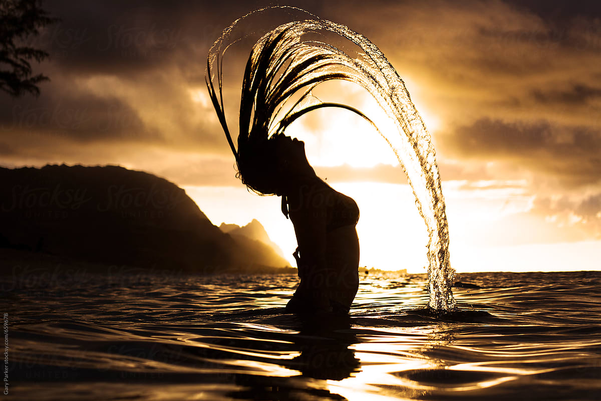 A Girl Flicking Her Hair Back In The Ocean Silhouetted By A Beautiful Sunset Del Colaborador