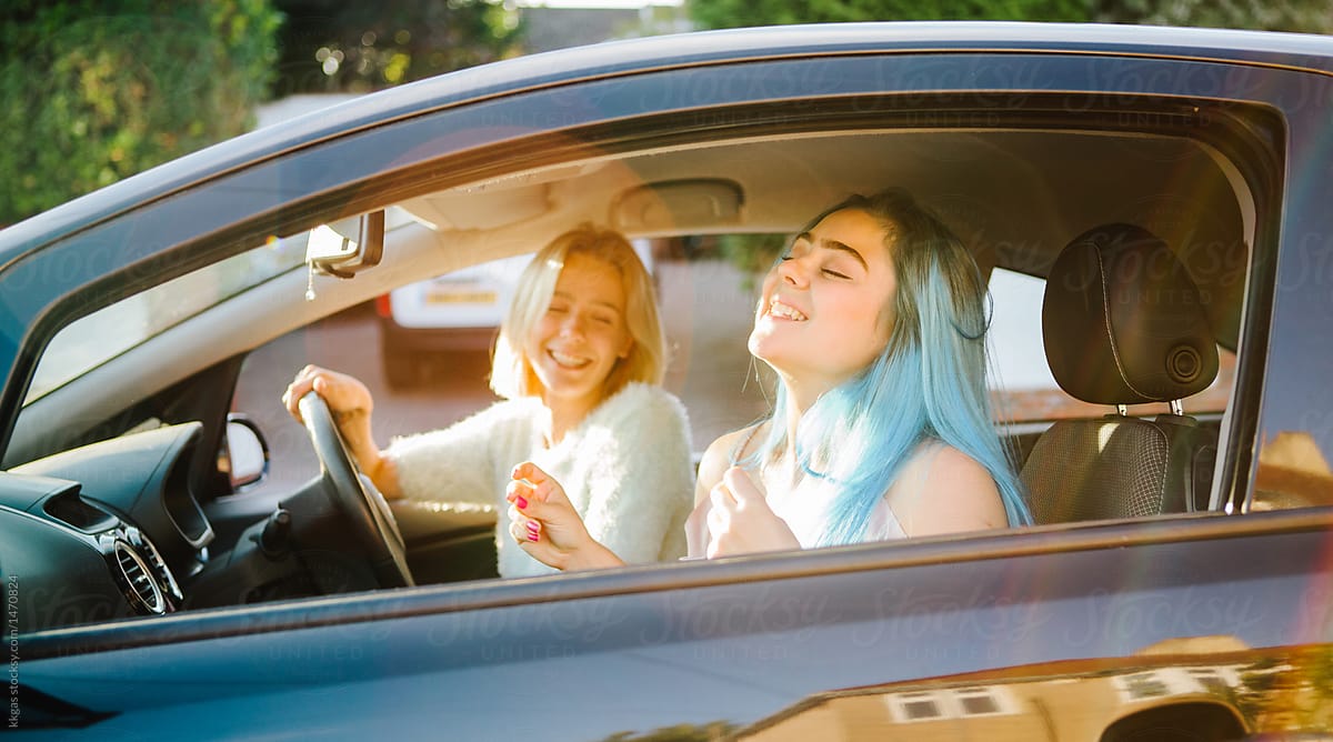 Young women singing along to music in their car