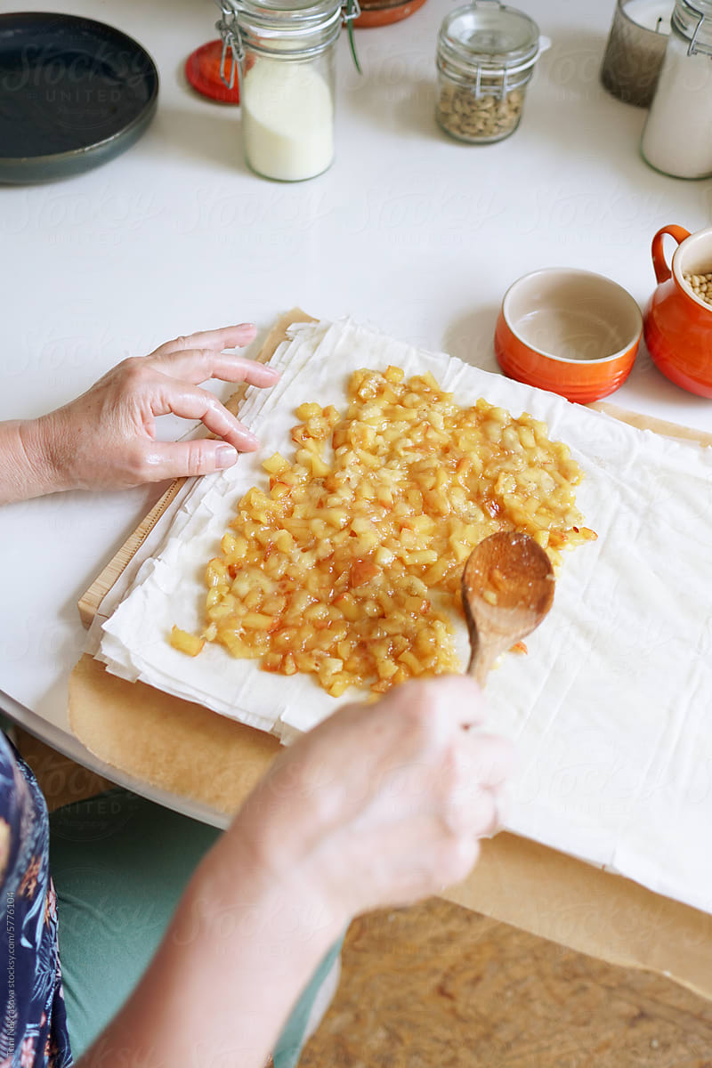 A woman putting apples on layers of dough while making a pie