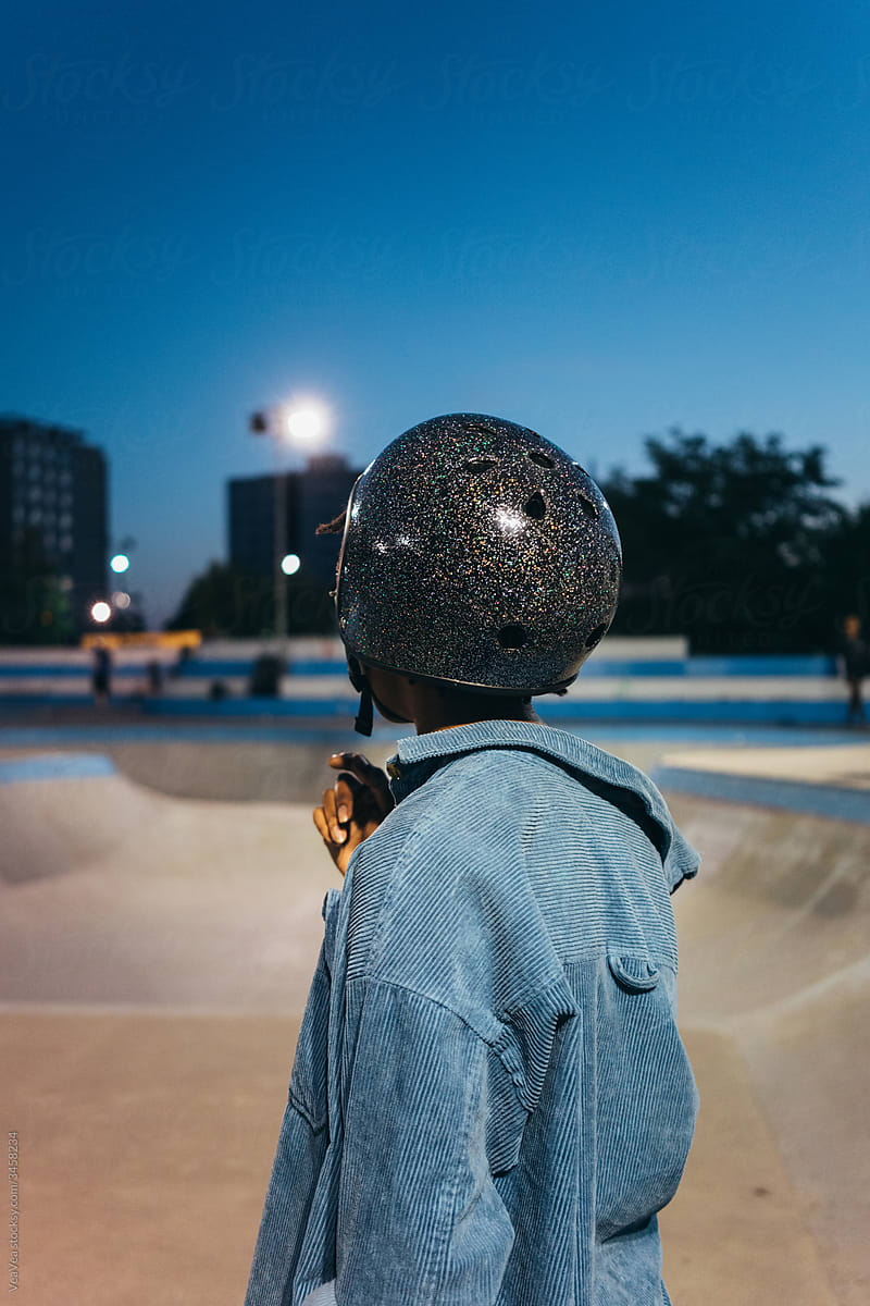 Unrecognizable woman wearing glittery helmet standing in front of a skate ramp