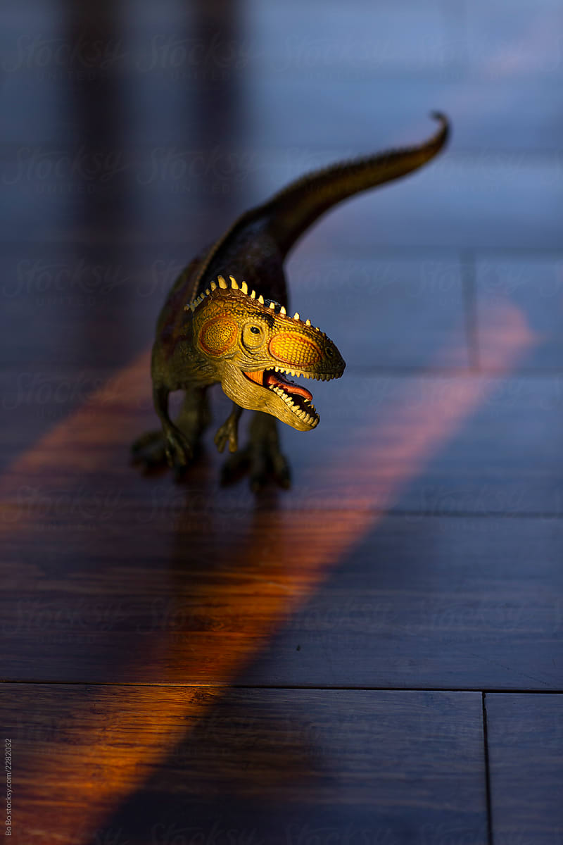 Toy dinosaur in sunset light on the floor at home