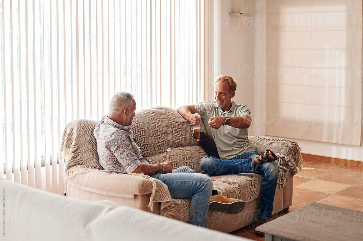 Mature male friends talking over beers at home