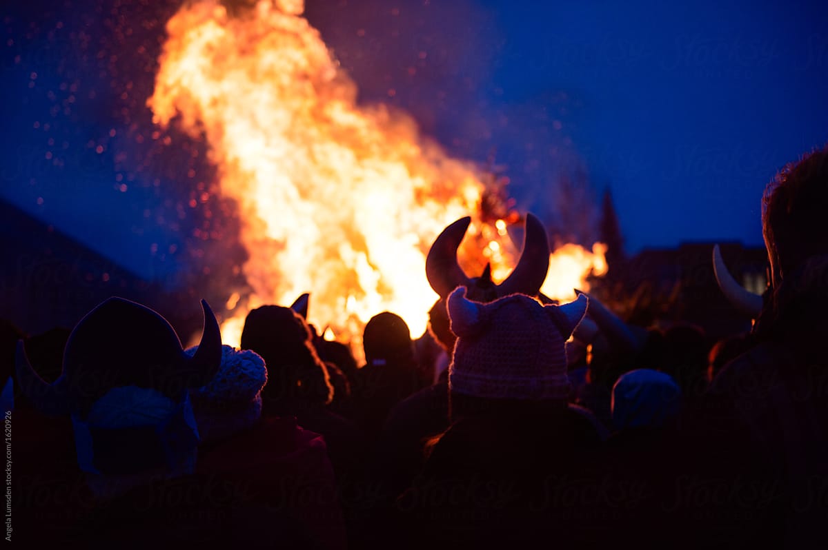 People wearing viking hats around a large bonfire at night