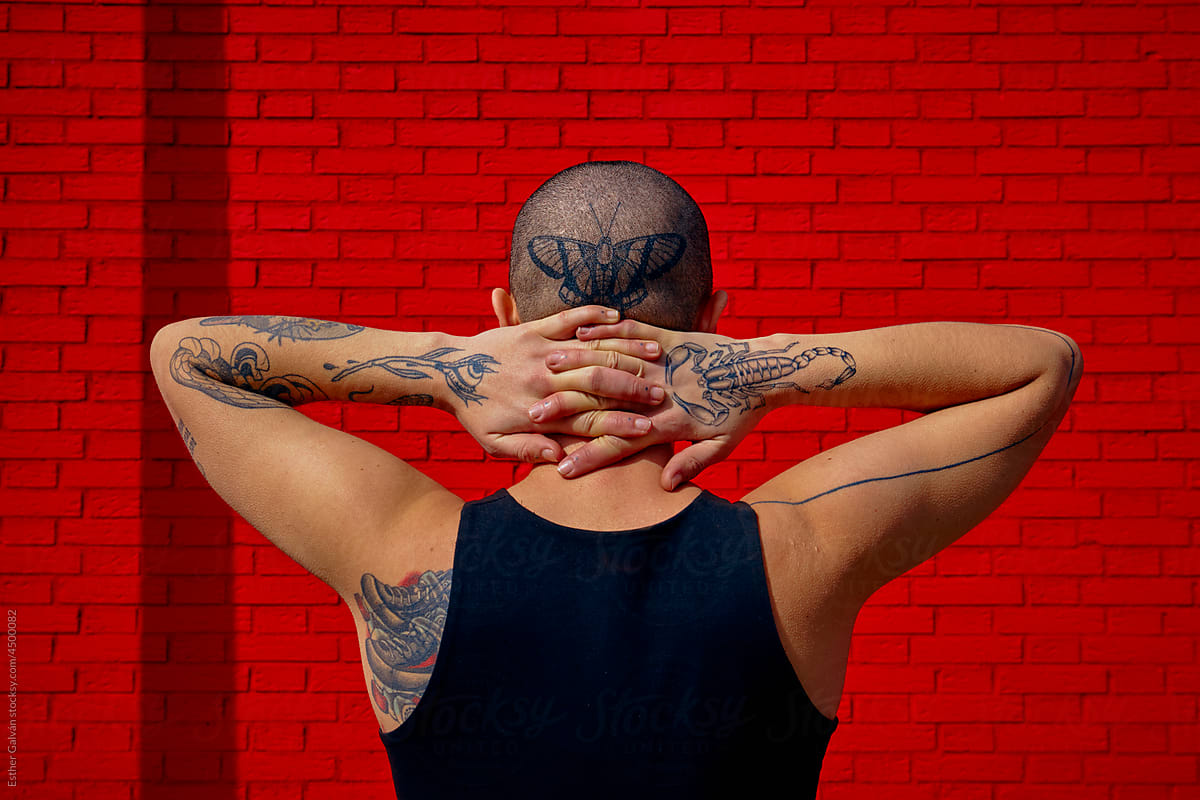 Back of a queer model with tattoos and shaved hair
