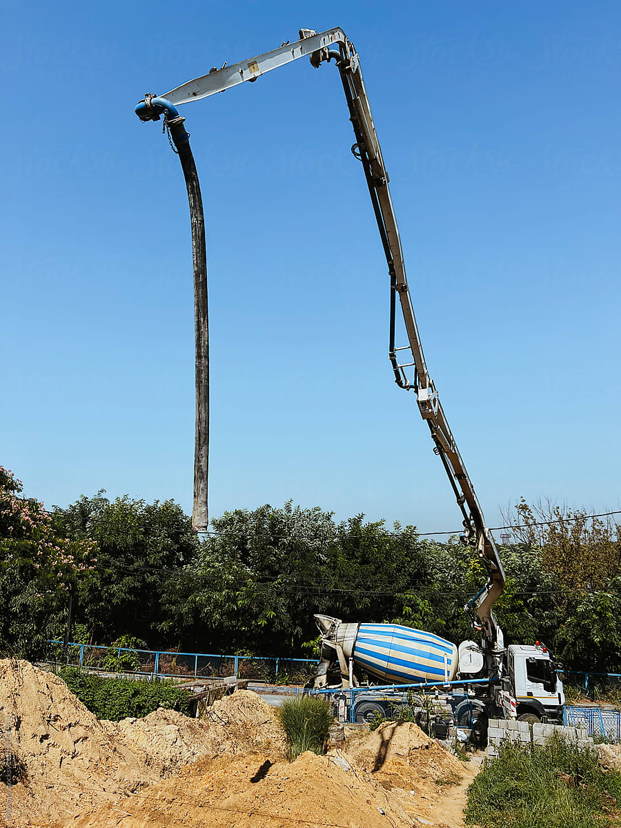 A truck-mounted concrete boom pump at the side of the road pouring con