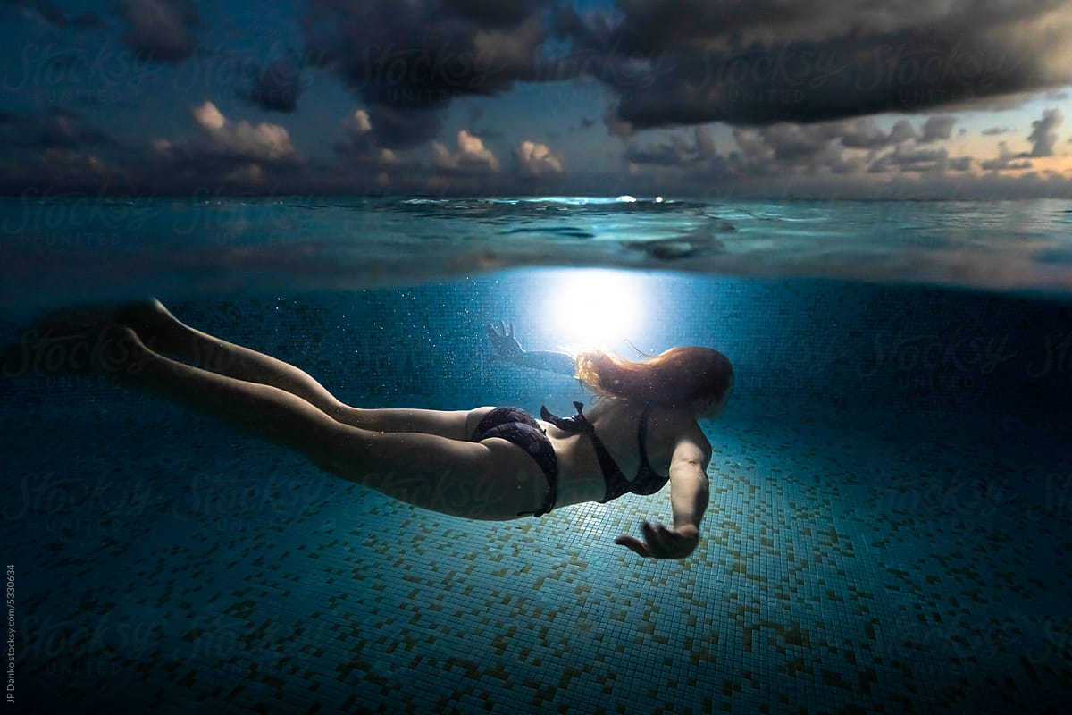 Woman Swimming Underwater at Tropical Resort Infinity Pool
