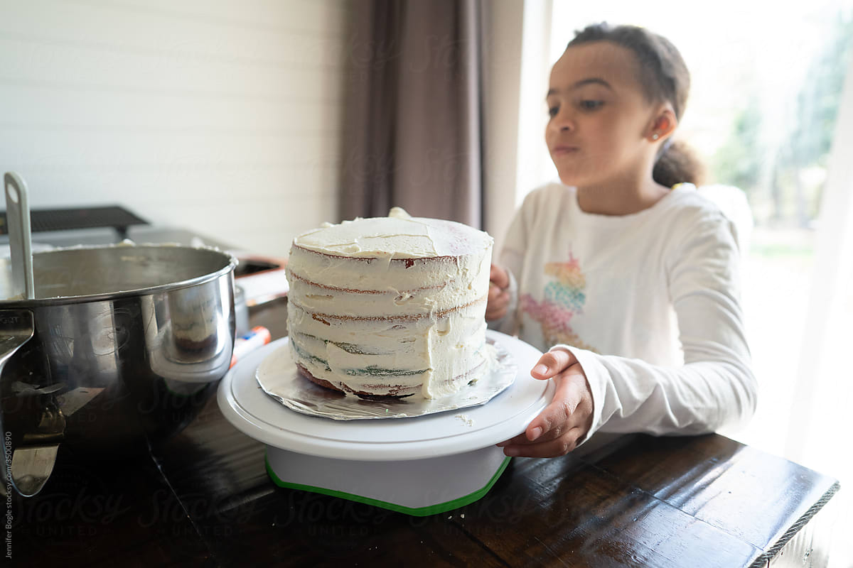 Girl frosts cake on stand