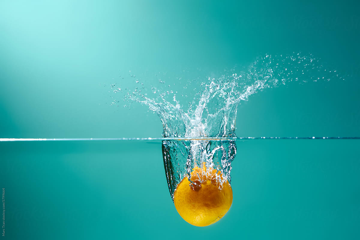 Orange falls deeply under water with a big splash.
