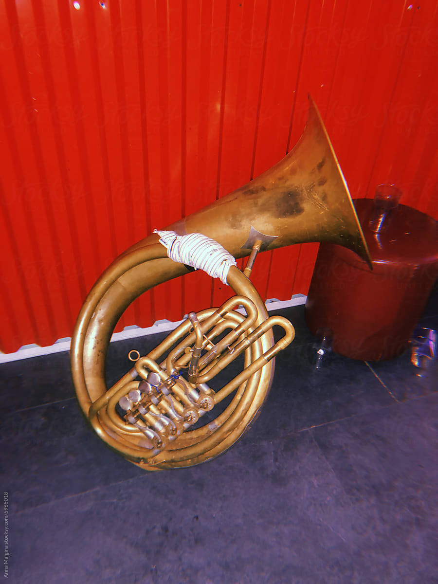Brass Tuba Resting Against Red Background
