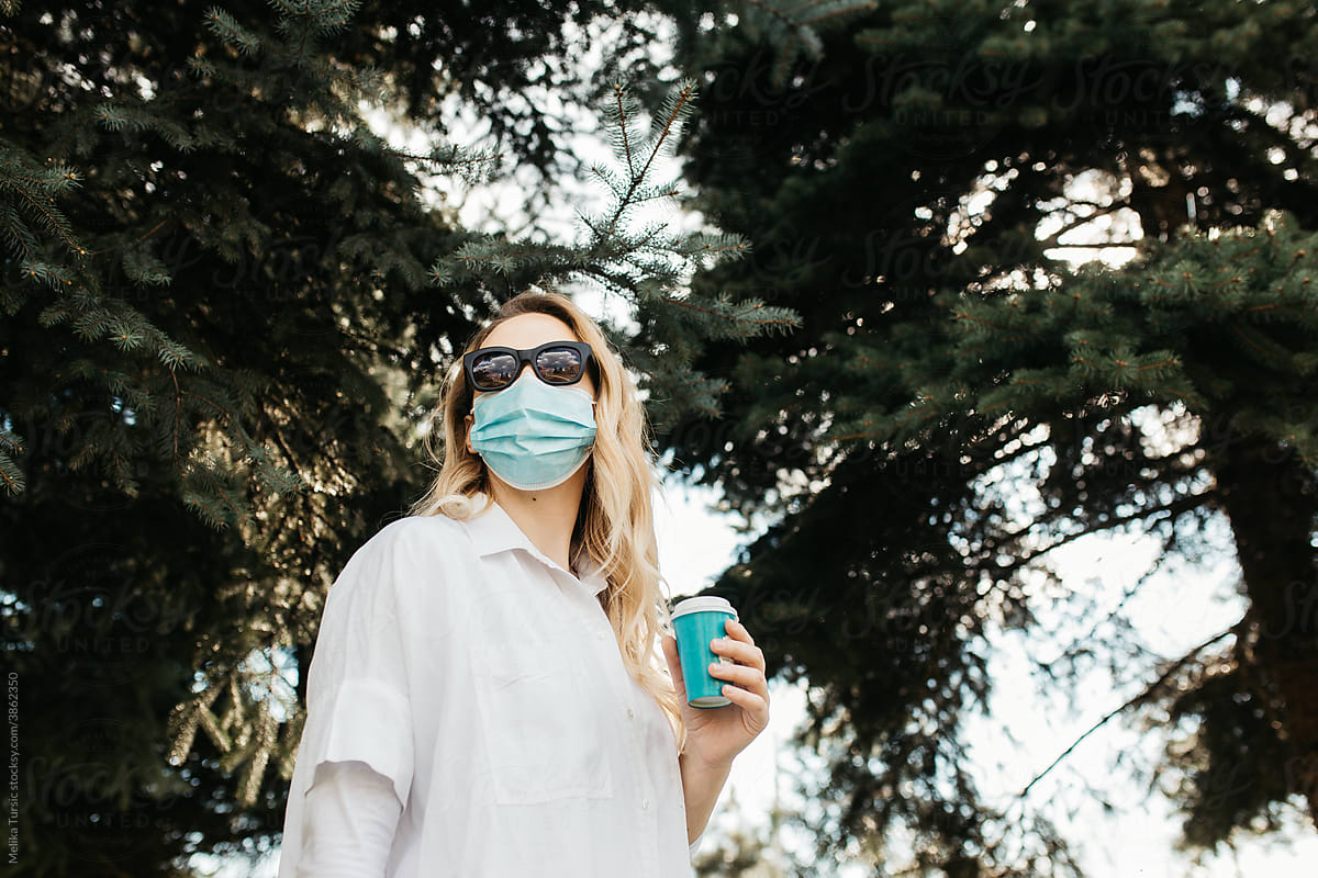 Girl wearing a mask and having coffee