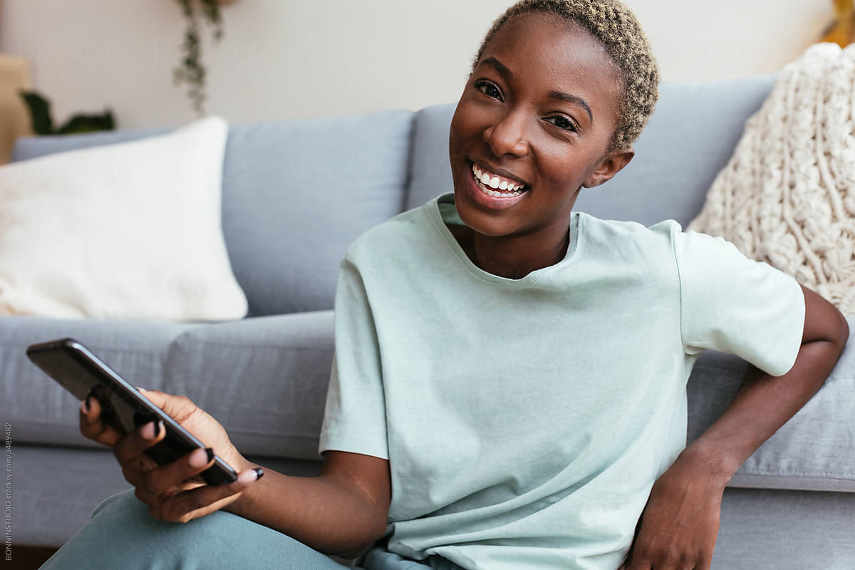 Happy black woman using smartphone at home