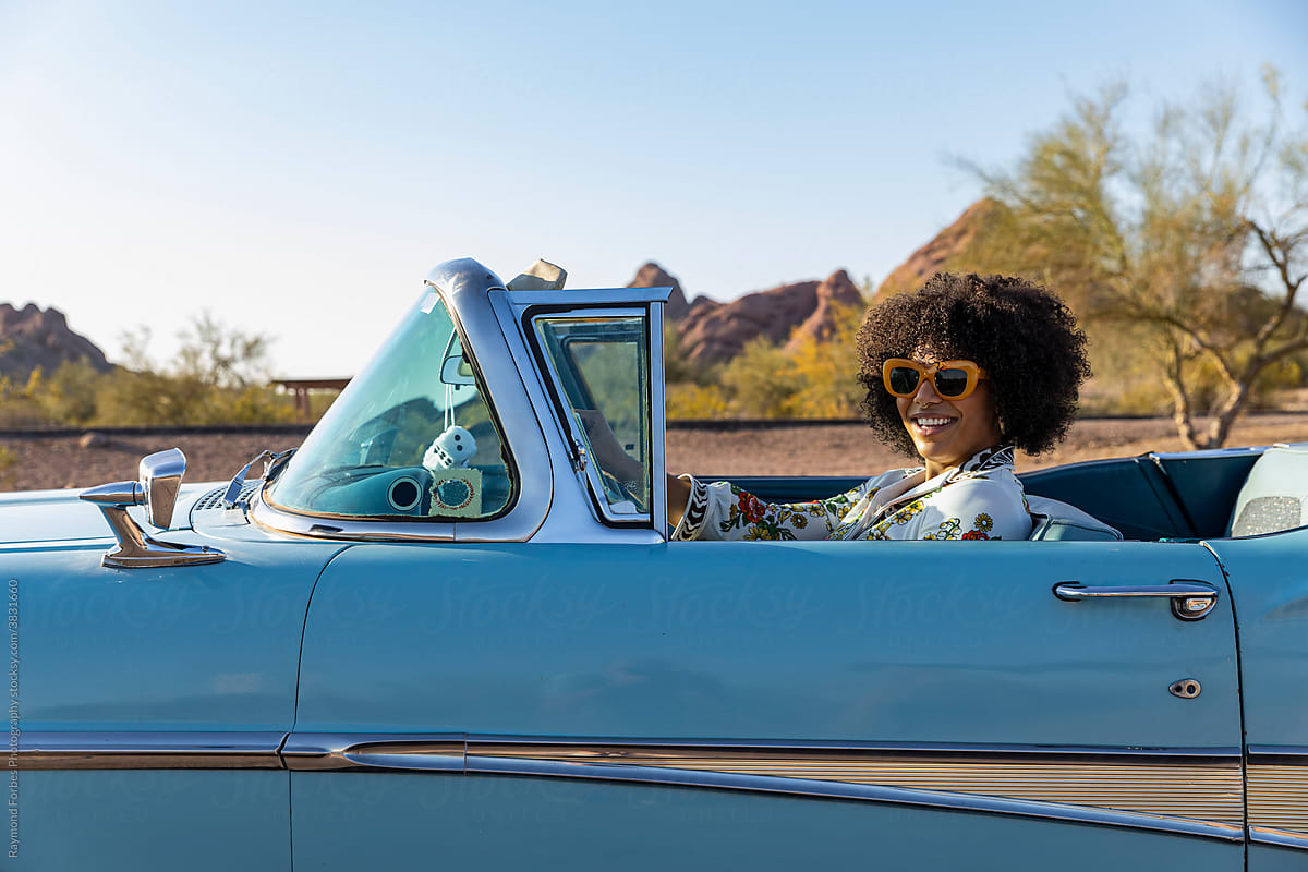 Happy Beautiful Black woman in Vintage Car behind the steering wheel